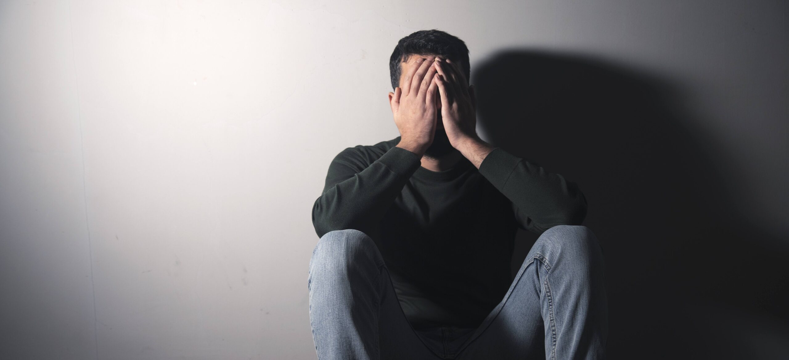 Stressed man seated on the floor, representing mental health issues